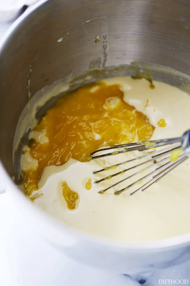 Pureed mangoes being mixed with zabaglione in a large metal bowl.