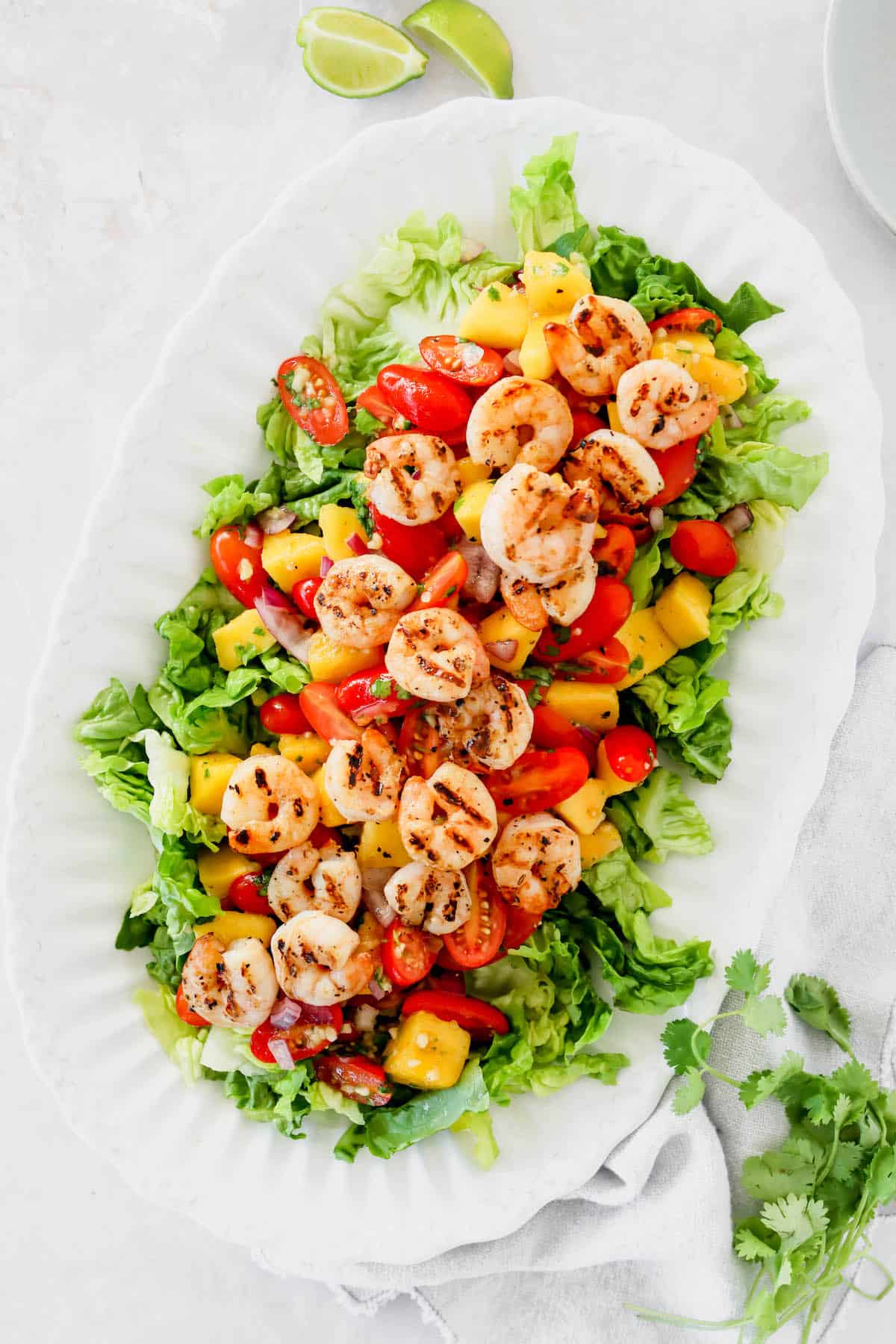 Overhead view of a grilled shrimp salad with mango and tomatoes