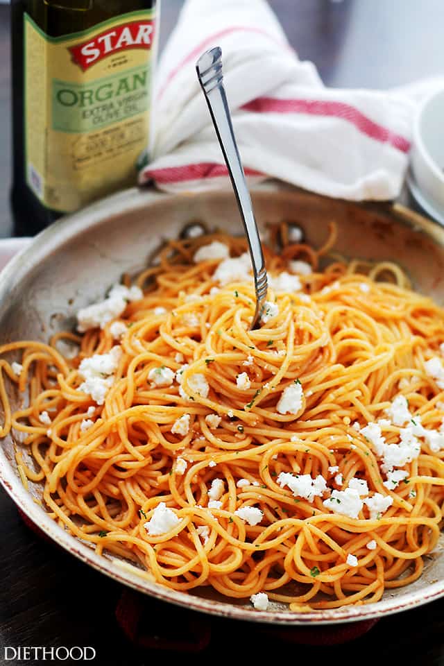 Twirling pasta to mix with ketchup and it's topped with crumbled feta cheese.