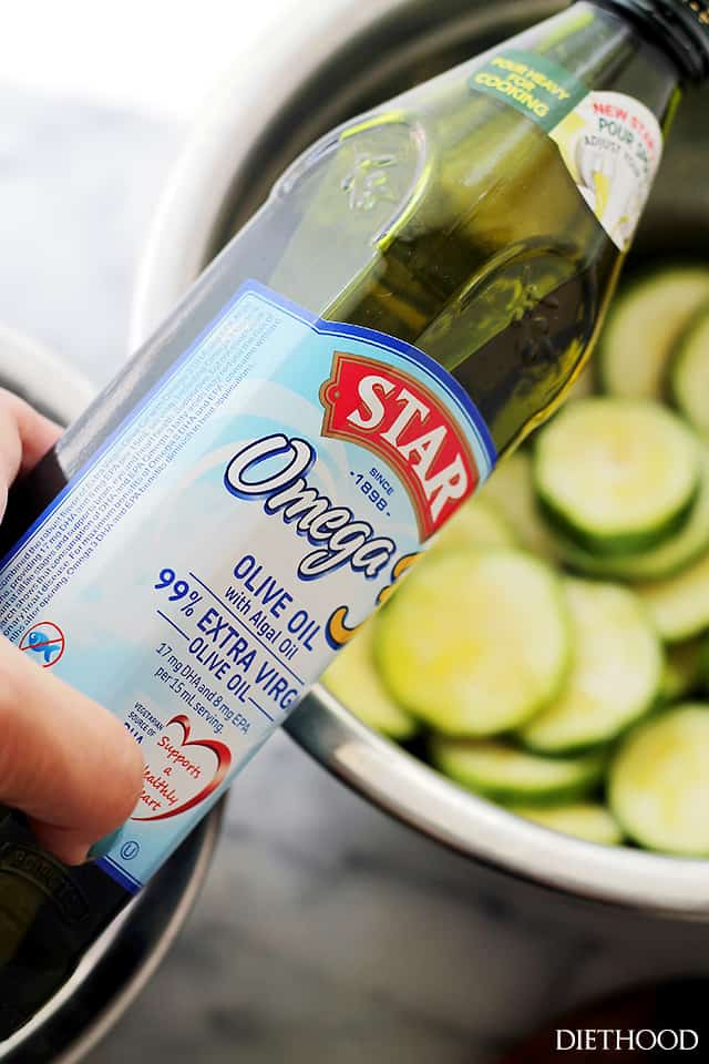 Pouring olive oil over zucchini slices.