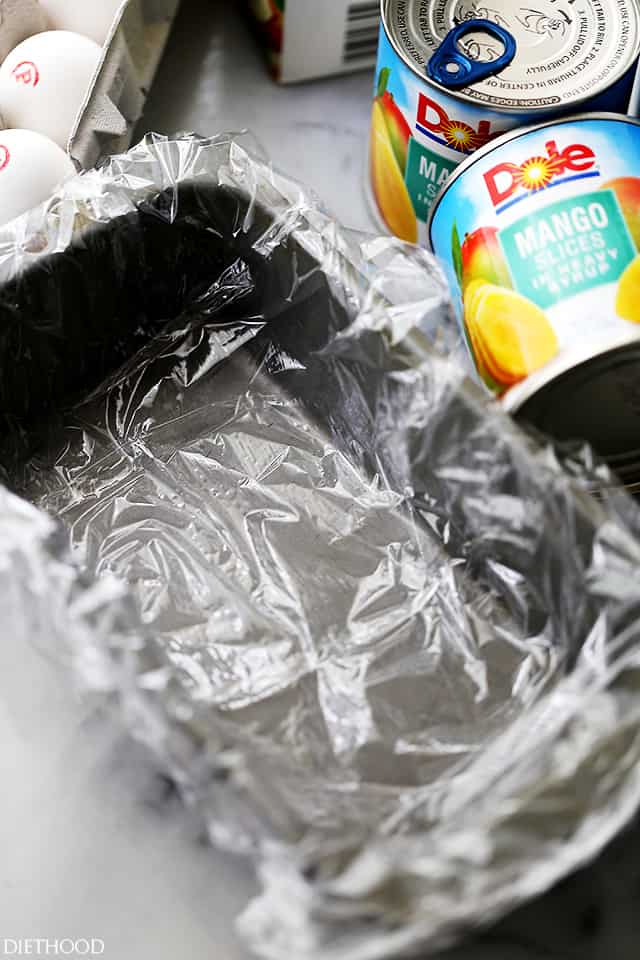 A loaf pan lined with cling wrap on top of a kitchen countertop