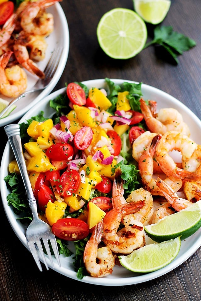 Mango and Shrimp Salad served in white salad bowls with lime wedges. 