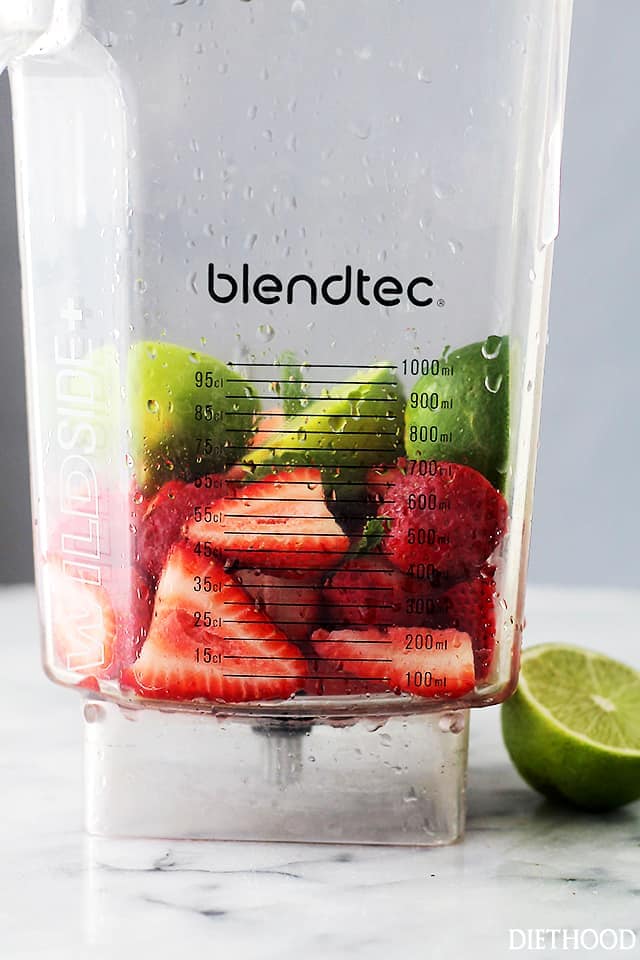 Strawberries and limes in a blender.