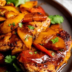 Close up view of Jamaican jerk chicken topped with stone fruit on a plate.