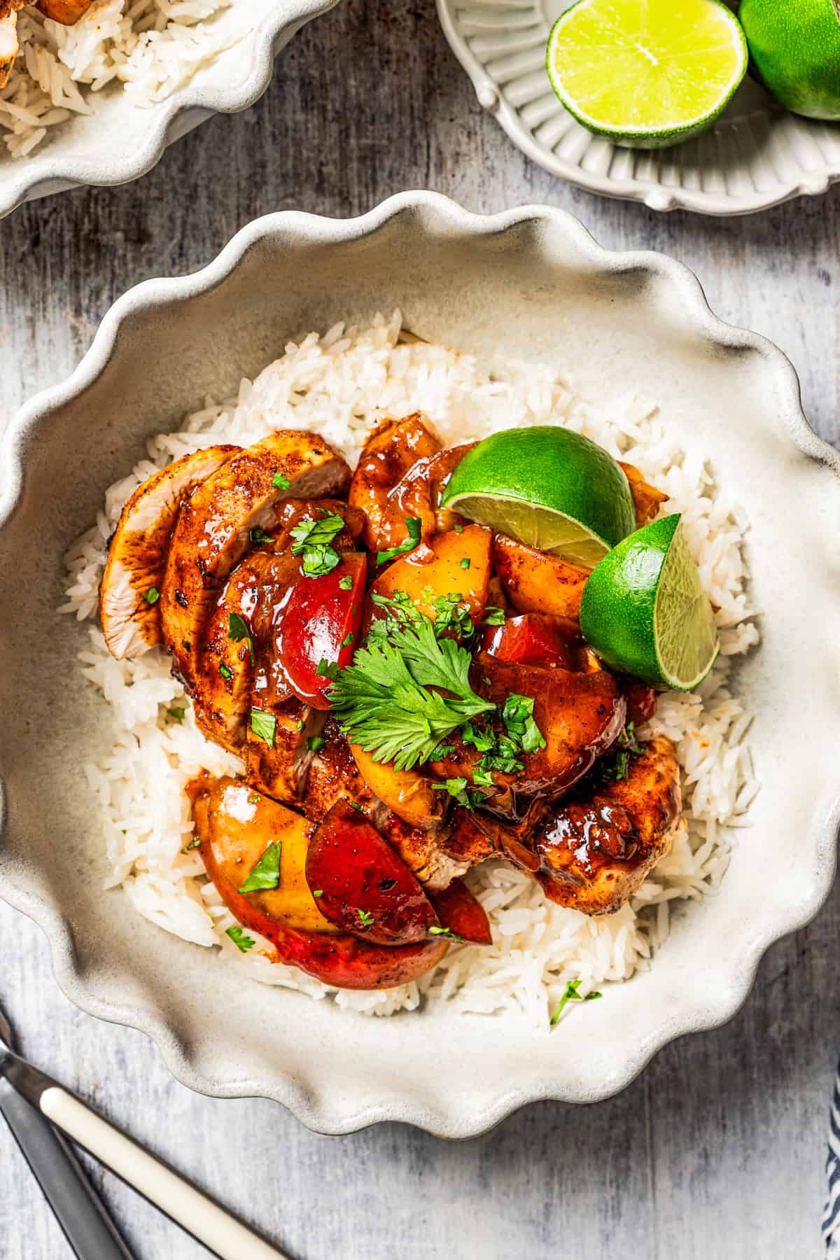 Sliced Jamaican jerk chicken served over rice with a stone fruit sauce and lime.