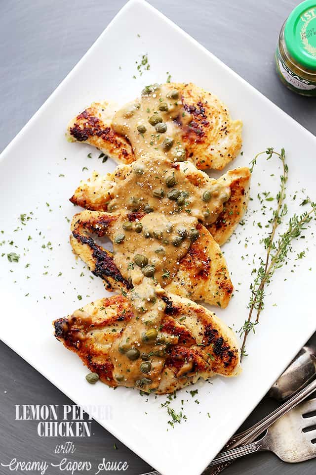 Chicken smothered in creamy lemon caper sauce on a plate with silverware beside it