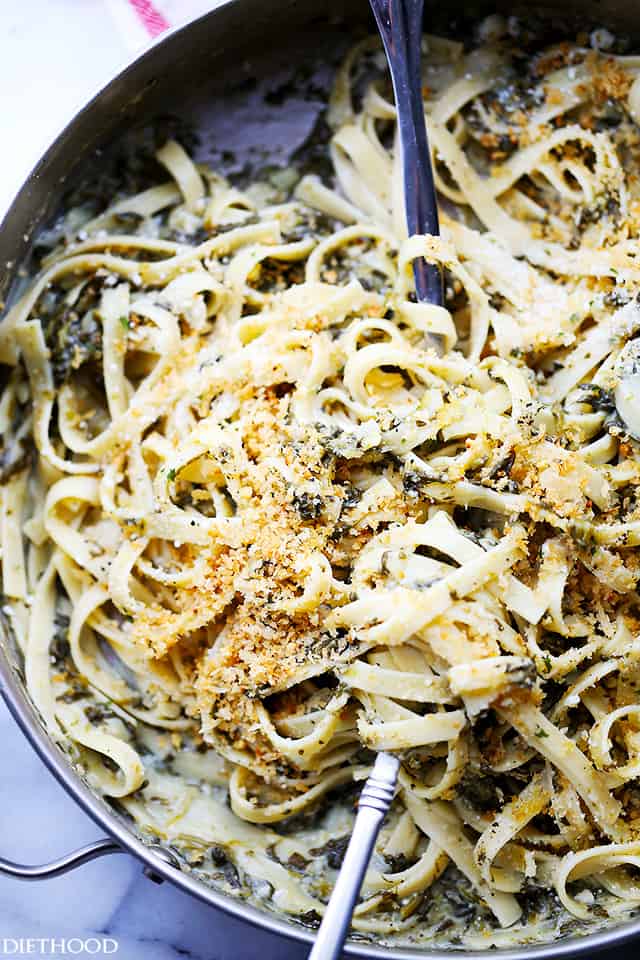 Overhead view of spinach fettuccine in a skillet with a serving spoon.