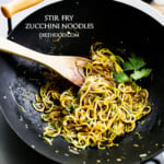 cooking spiralized zucchini and onions in a wok.