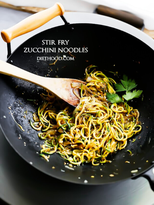 cooking spiralized zucchini and onions in a wok.