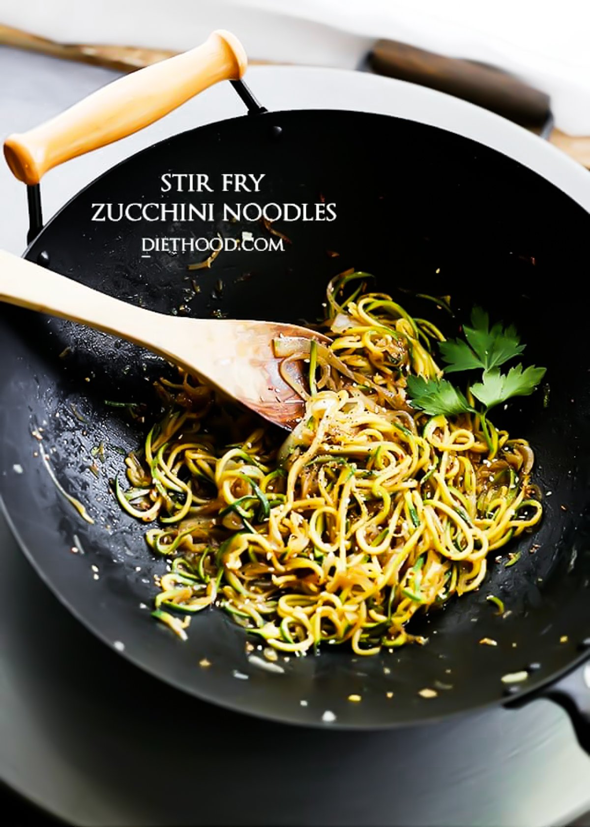 cooking spiralized zucchini and onions in a wok.