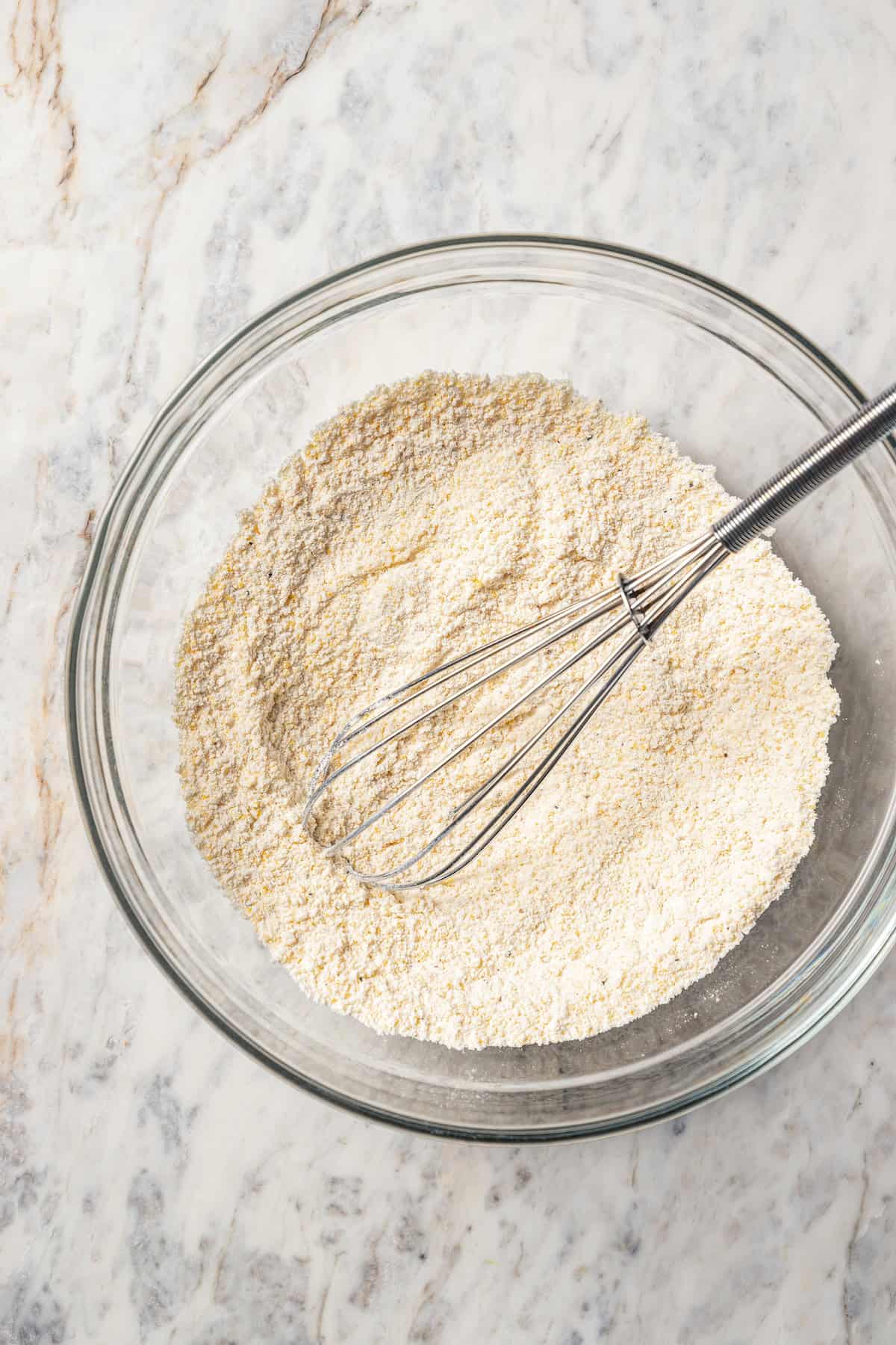 Dry ingredients combined in a glass bowl with a whisk.