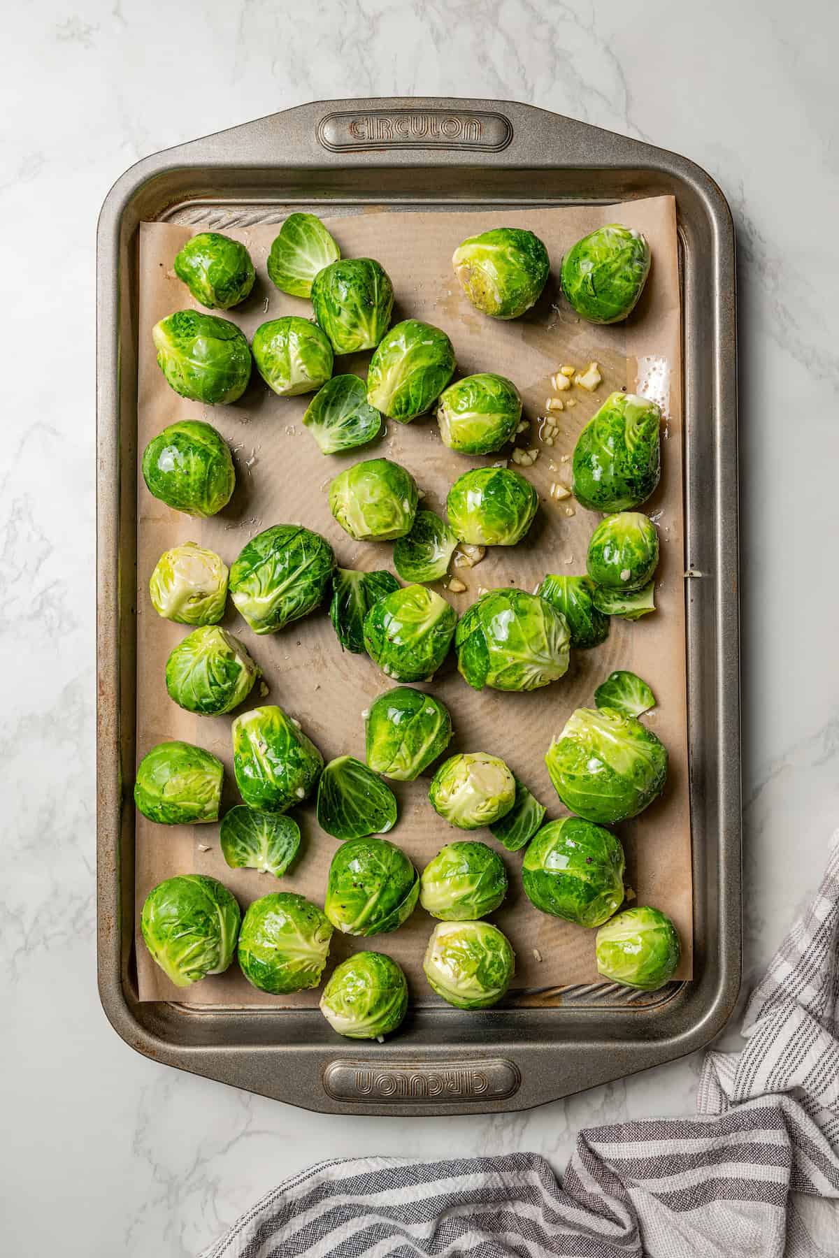 Overhead view of seasoned Brussels sprouts on a baking sheet.