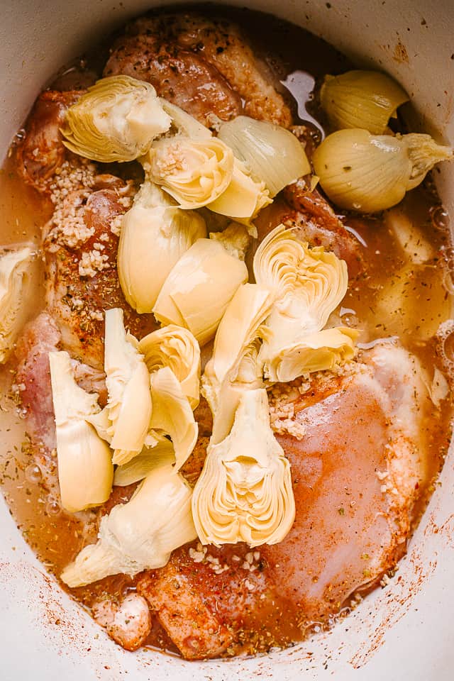 Artichoke hearts layered over chicken thighs in the crock pot.
