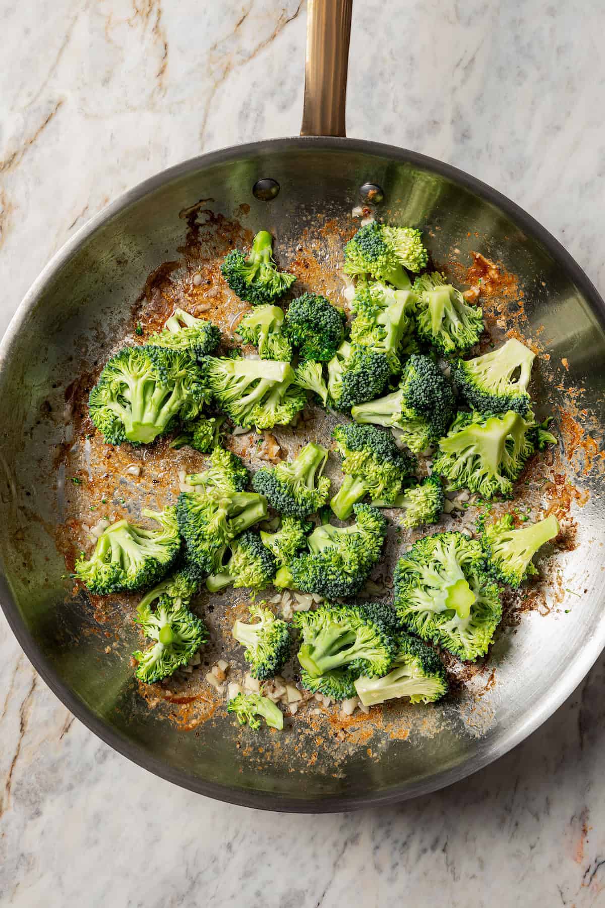 Broccoli florets added to a skillet.