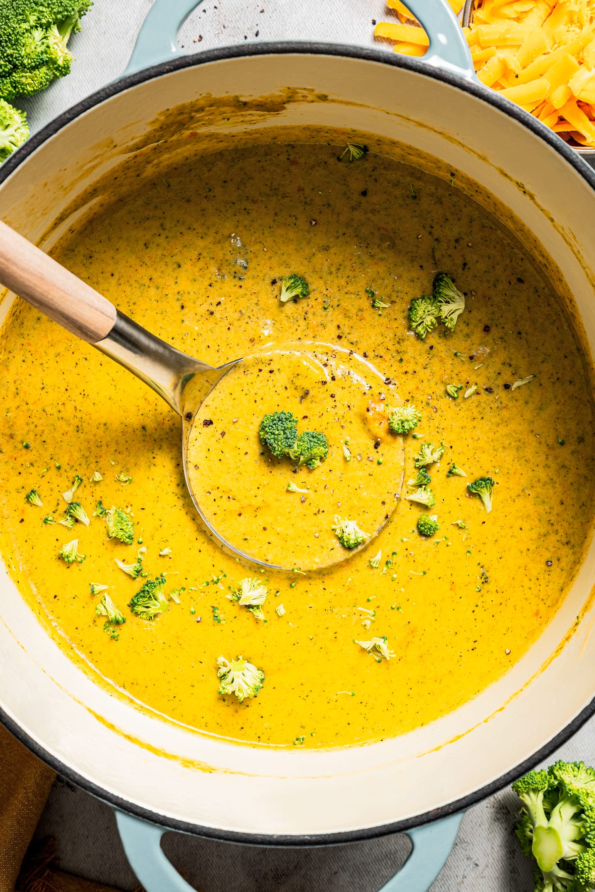 Overhead image of broccoli cheese soup in a soup pot with a ladle.
