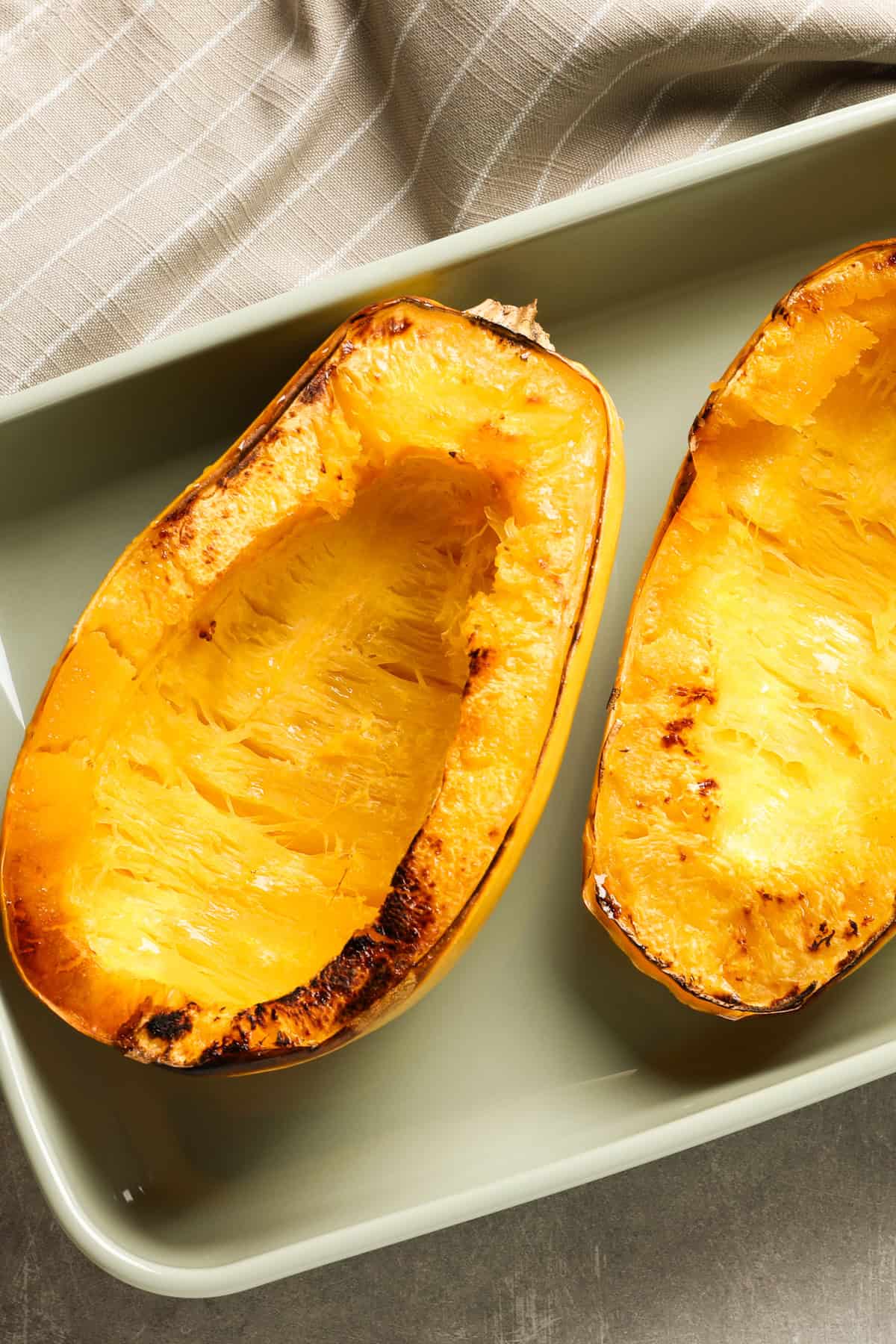 Spaghetti squash cut in half and set on a baking sheet.