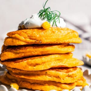 A stack of pancakes topped with creamy yogurt sauce.