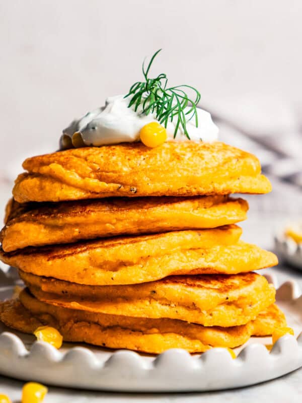 A stack of pancakes topped with creamy yogurt sauce.