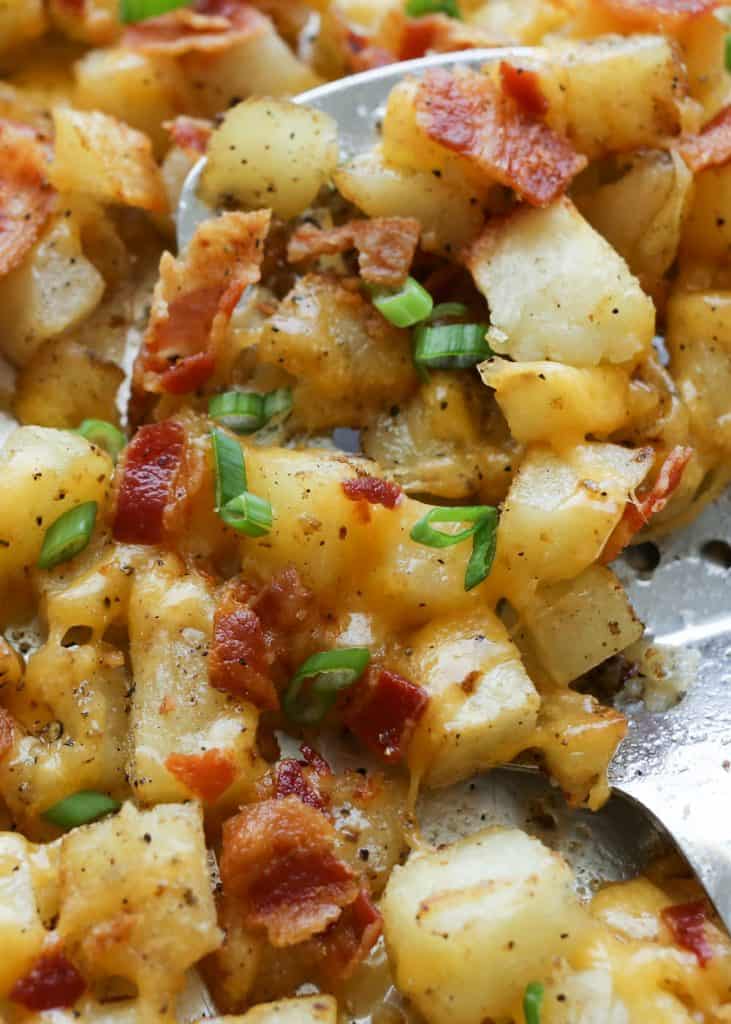 Crispy cheese and bacon topped diced potatoes on a baking sheet