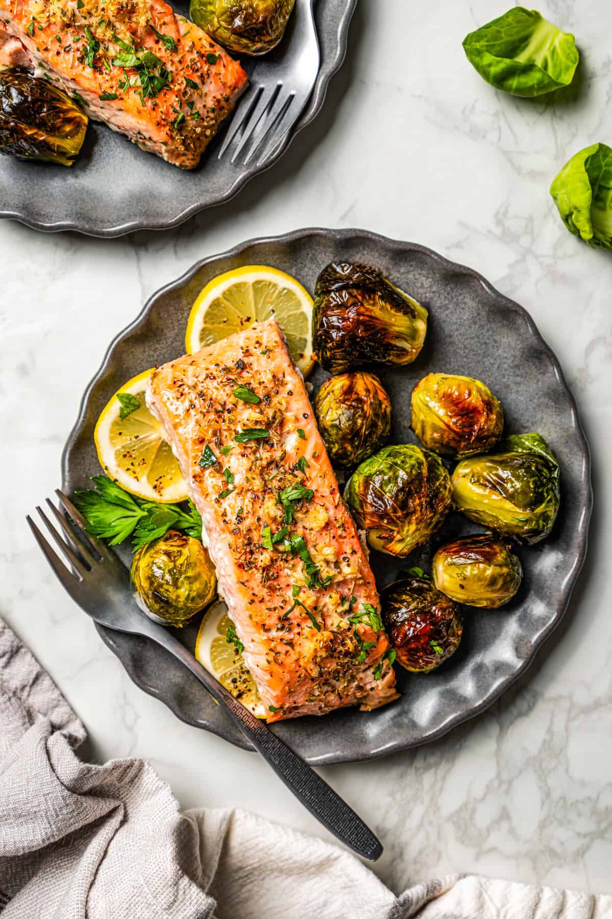 Salmon filet served on a dinner plate with a side of brussel sprouts.