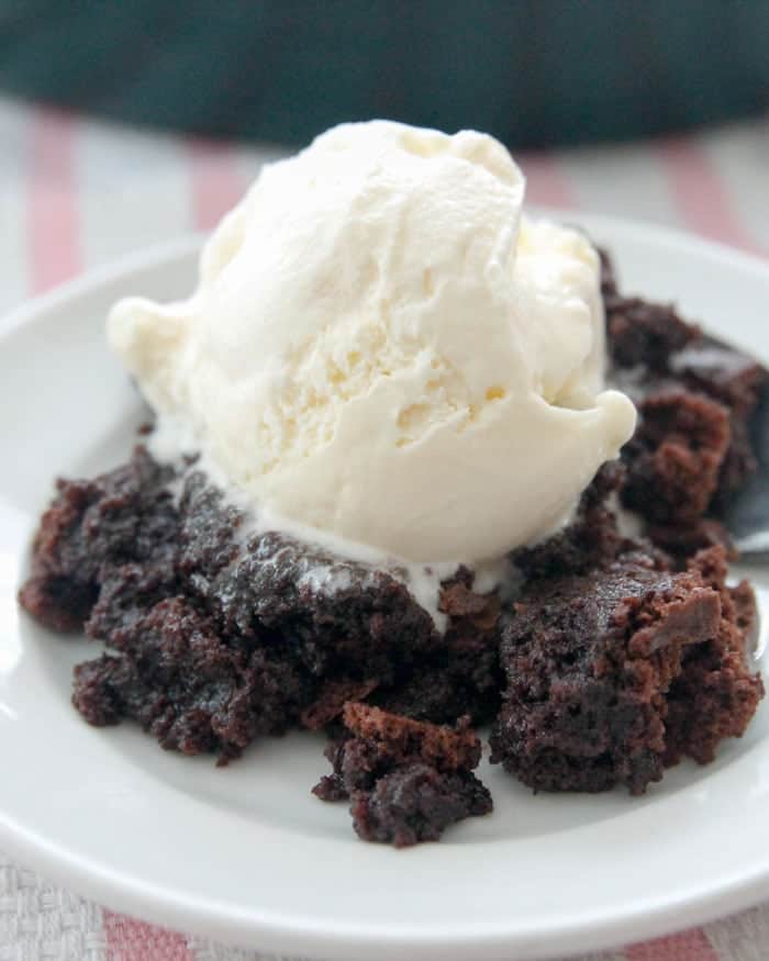 A serving of chocolate brownie pudding with ice cream on a plate
