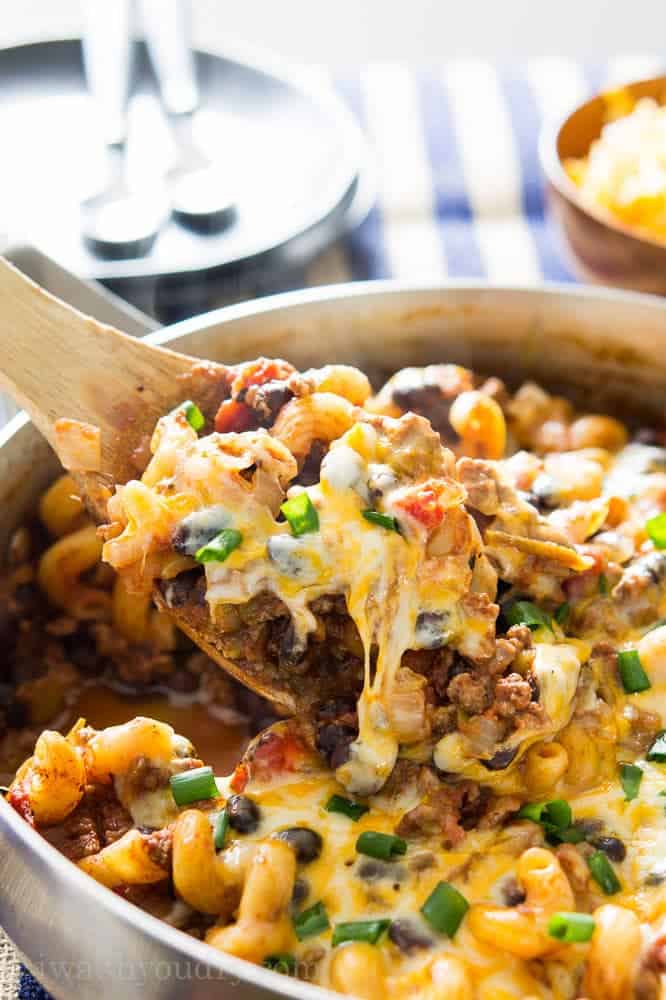 Chili pasta skillet topped with scallions and melted cheese
