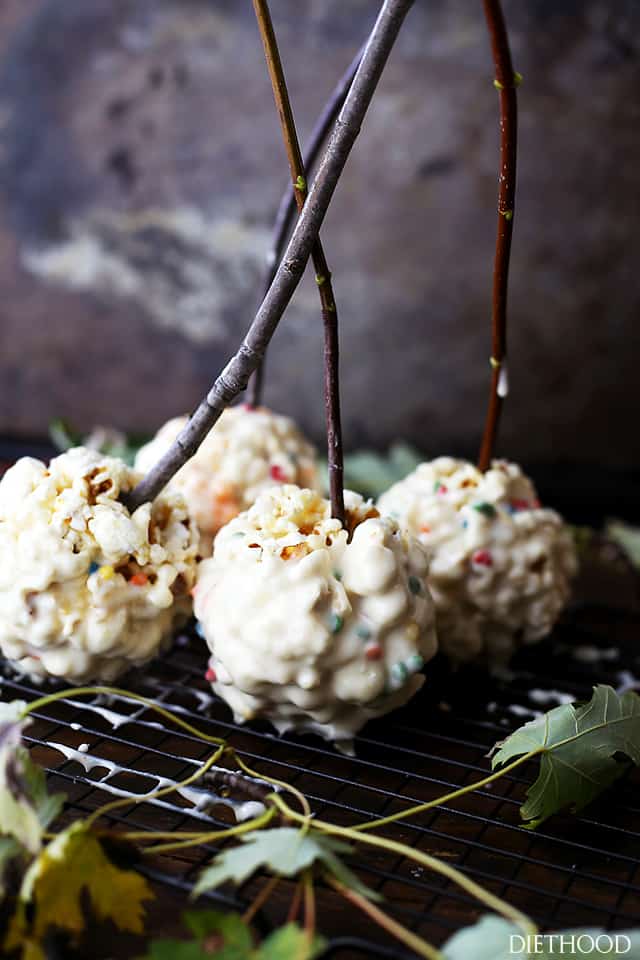 Frosted Marshmallow Popcorn Balls - Held together with a mixture of melted marshmallows and butter, and dipped in Frosting, these Marshmallow Popcorn Balls make great treats for kids, especially around Halloween!