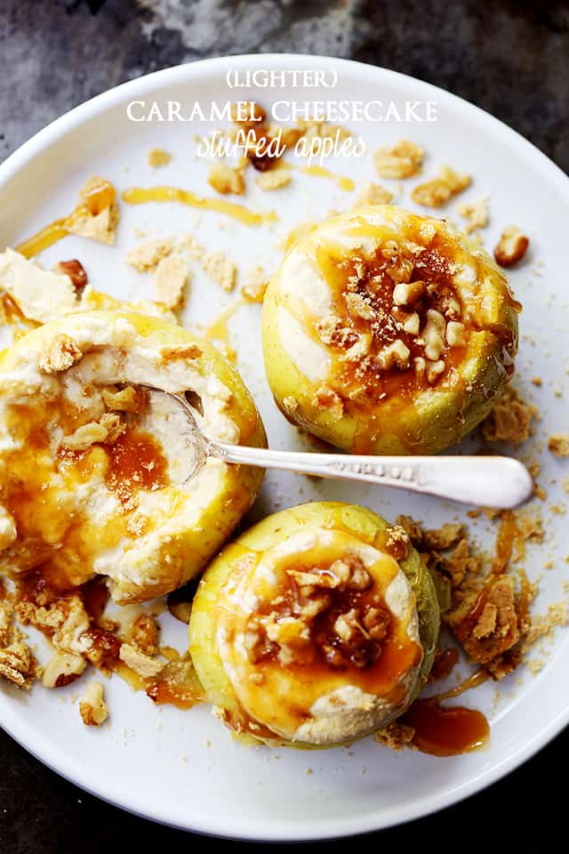 Overhead image of a plate with three baked apples stuffed with cheesecake filling and topped with caramel drizzle and nuts.