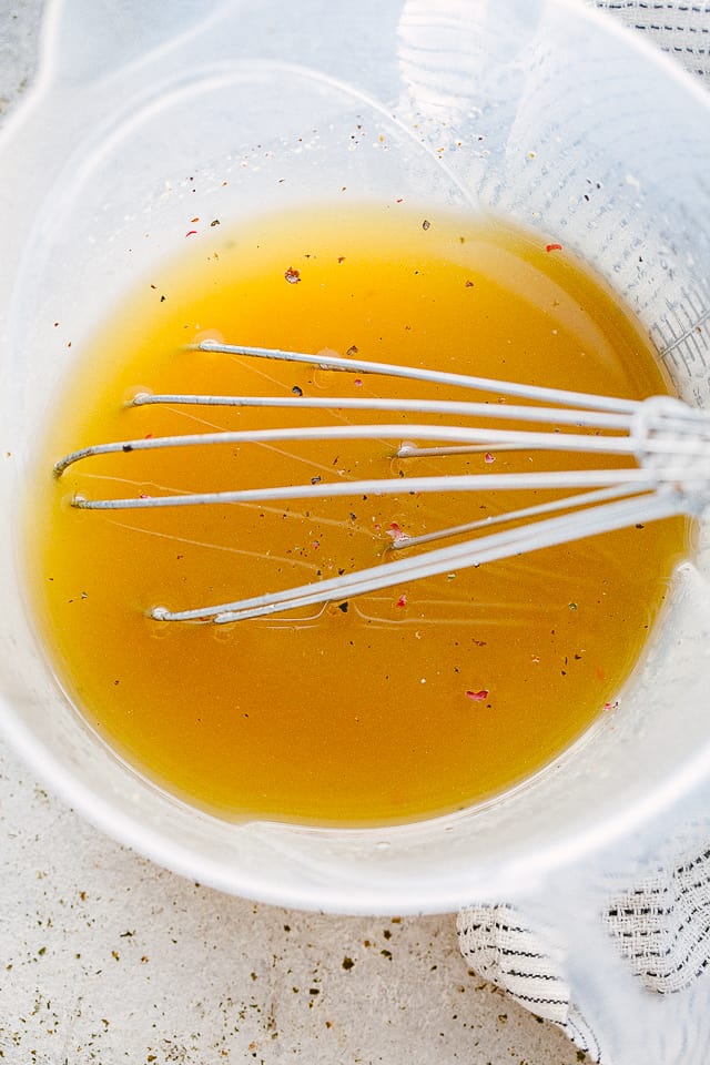 Whisking dijon mustard and balsamic vinegar in a large measuring cup.