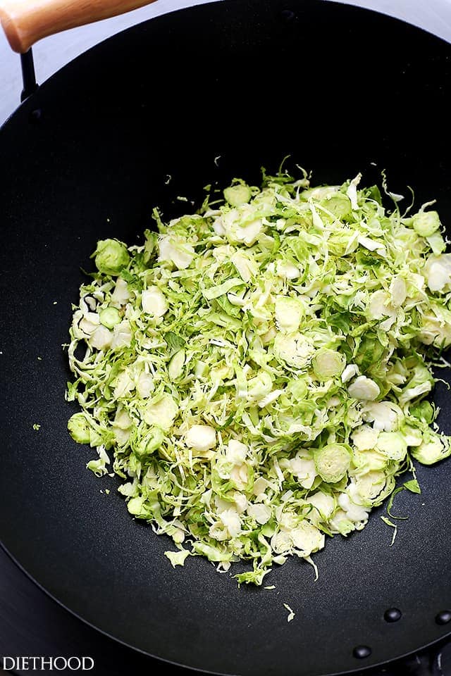 Cooking shaved brussel sprouts in a dark skillet.