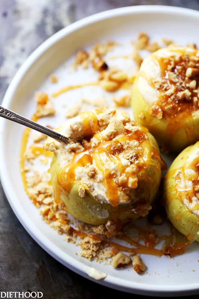 Photo of a plate with three baked apples stuffed with cheesecake filling and topped with caramel drizzle and nuts.