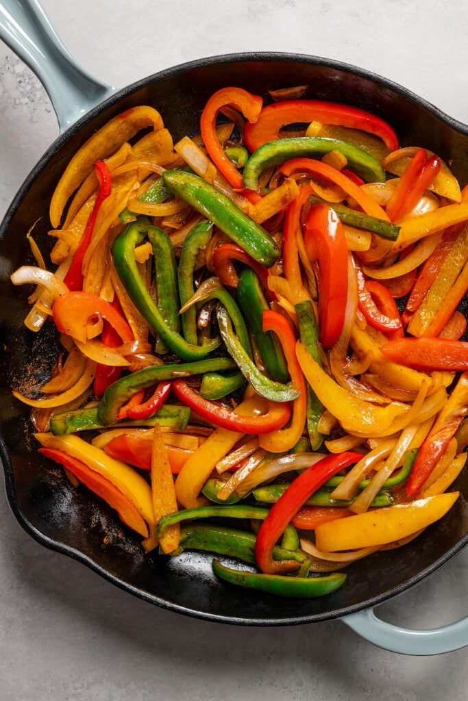 Sauteed bell peppers and onions in a cast iron skillet.