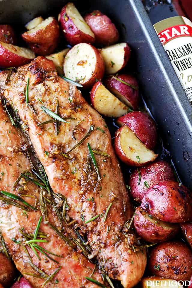 Fully cooked balsamic roasted pork tenderloin surrounded by potatoes in a roasting pan