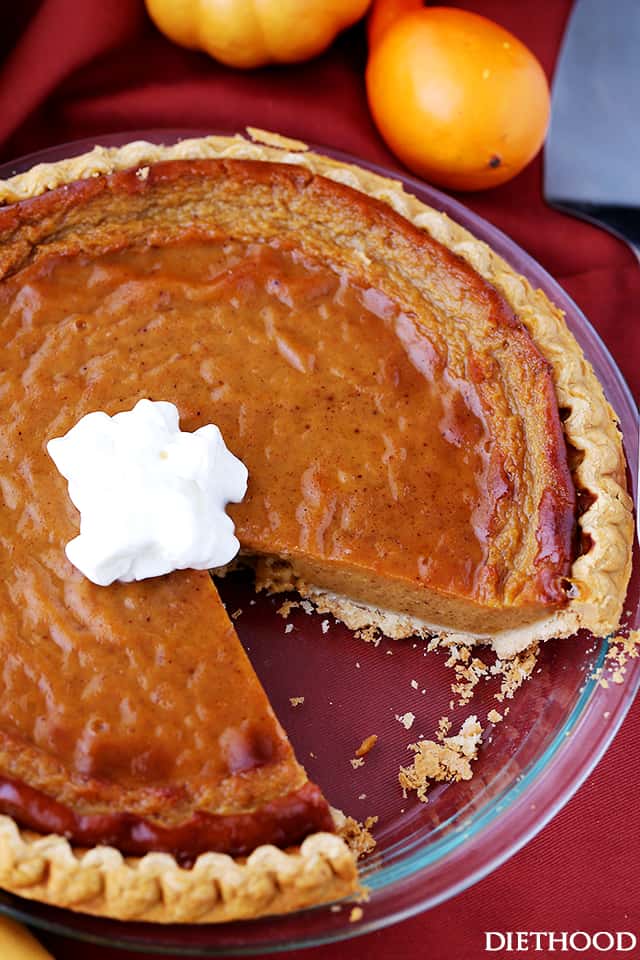 Baked Healthy Pumpkin Pie with one slice missing, topped with low-fat whipped cream