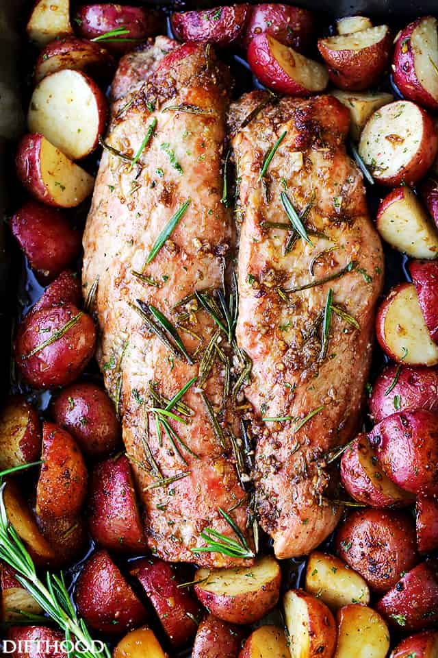 Bird's eye view of fully cooked pork tenderloin surrounded by potatoes in a roasting pan