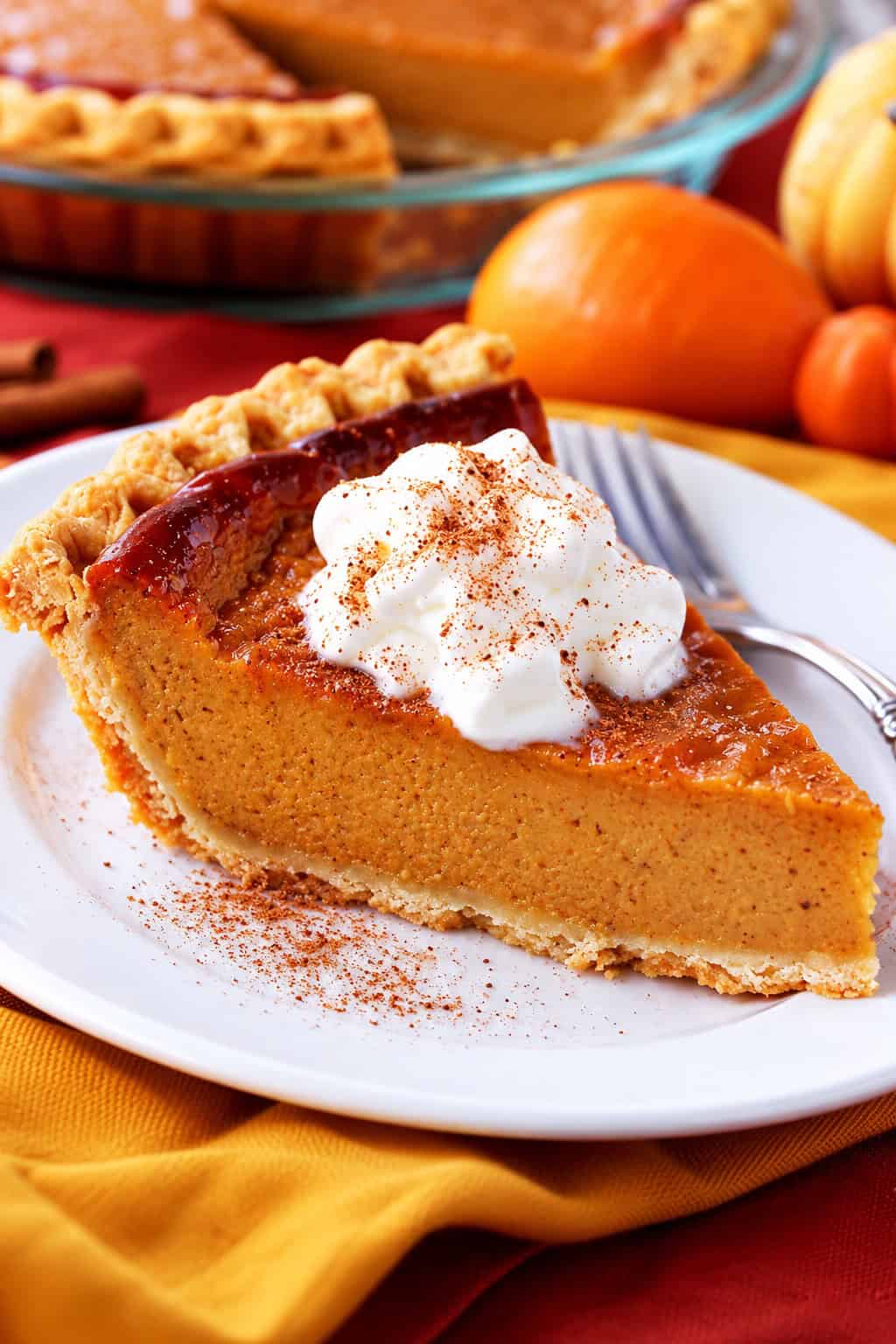 This easy pumpkin pie recipe is perfect for Thanksgiving dessert! It’s a rich and creamy pie with a lighter take on the classic treat. A slice of pumpkin pie on a plate.