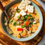 A bowl of crab soup garnished with saltine crackers, with a spoon resting in the bowl.