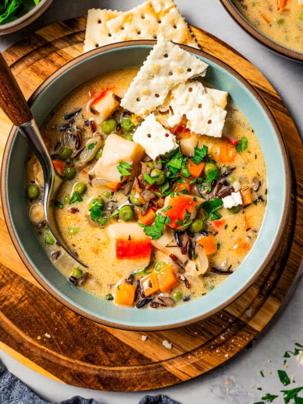 A bowl of crab soup garnished with saltine crackers, with a spoon resting in the bowl.