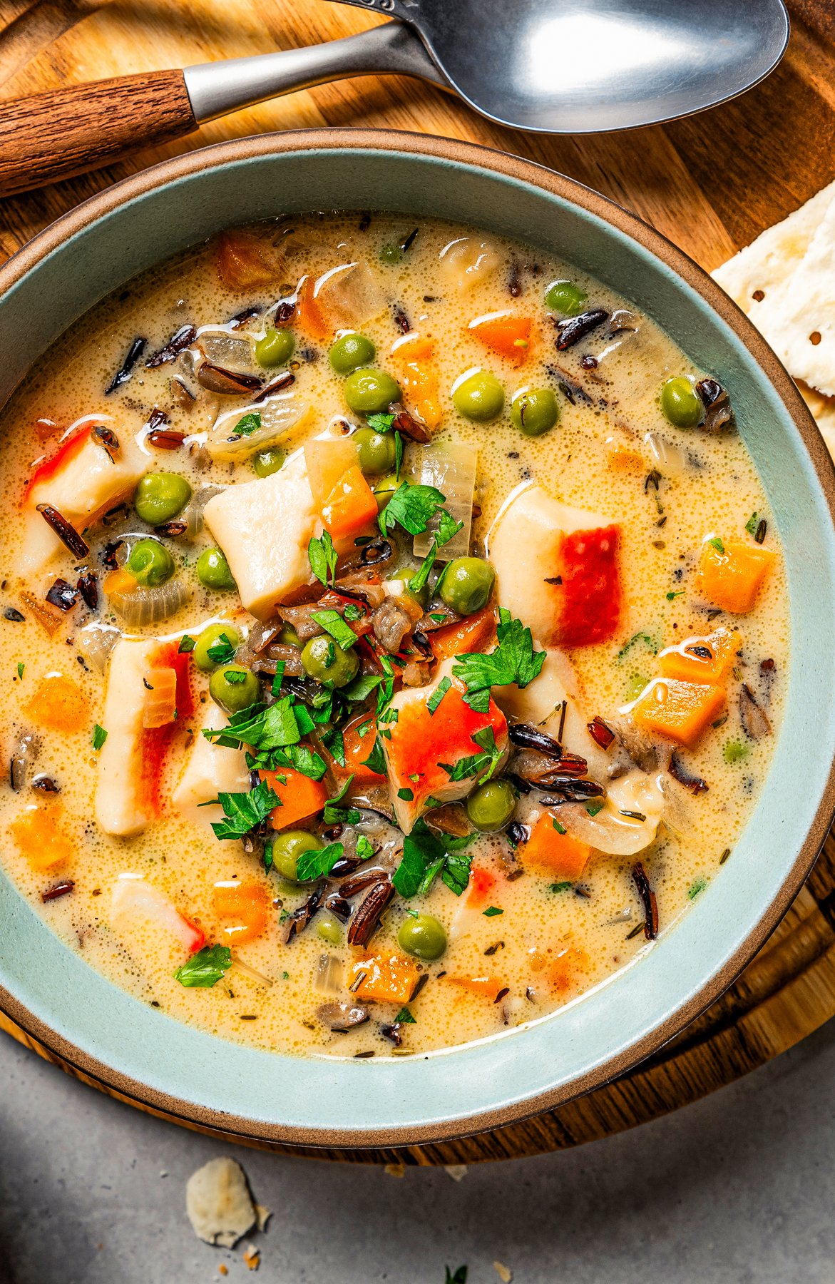 Close-up image of crab soup served in a bowl and garnished with fresh green herbs.