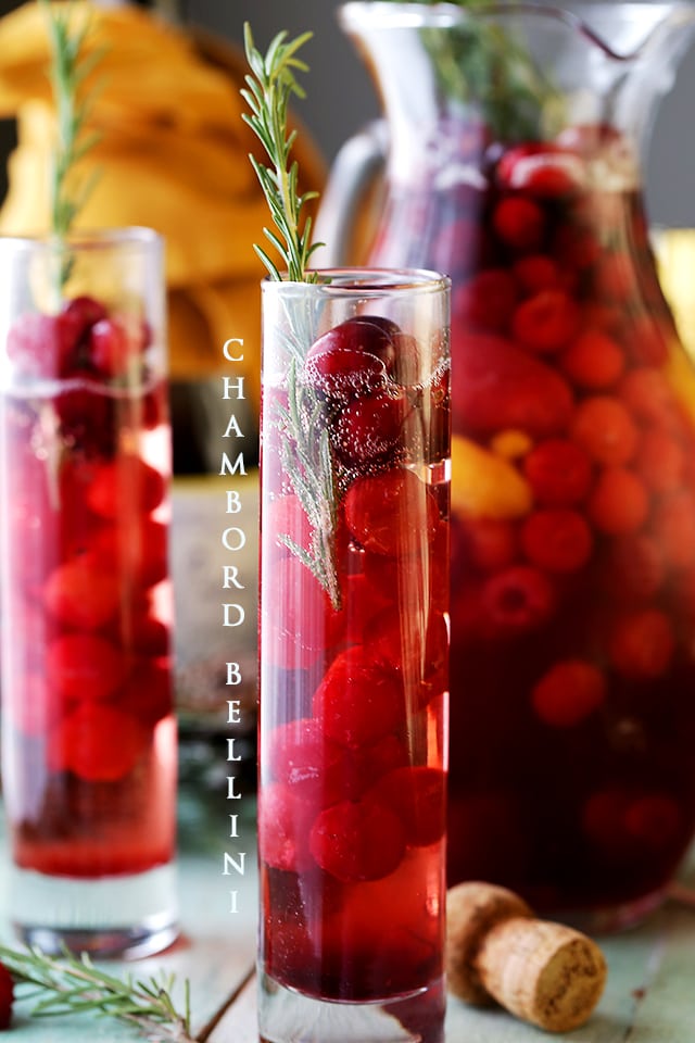 Chambord Bellini served in tall, narrow drinking glasses and garnished with a sprig of rosemary.
