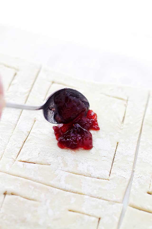 Adding a teaspoon of jam to the center of puff pastry dough.
