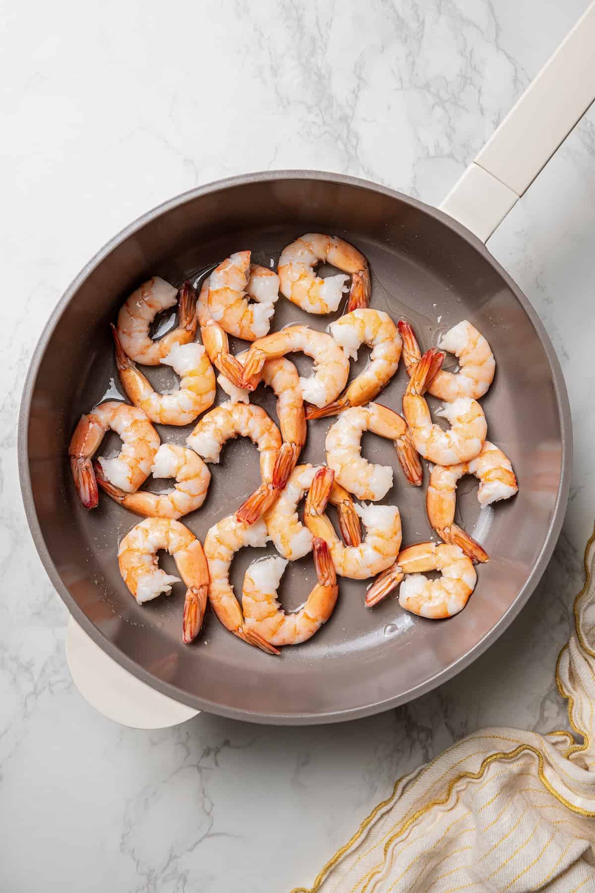 Jumbo shrimp added to a skillet.