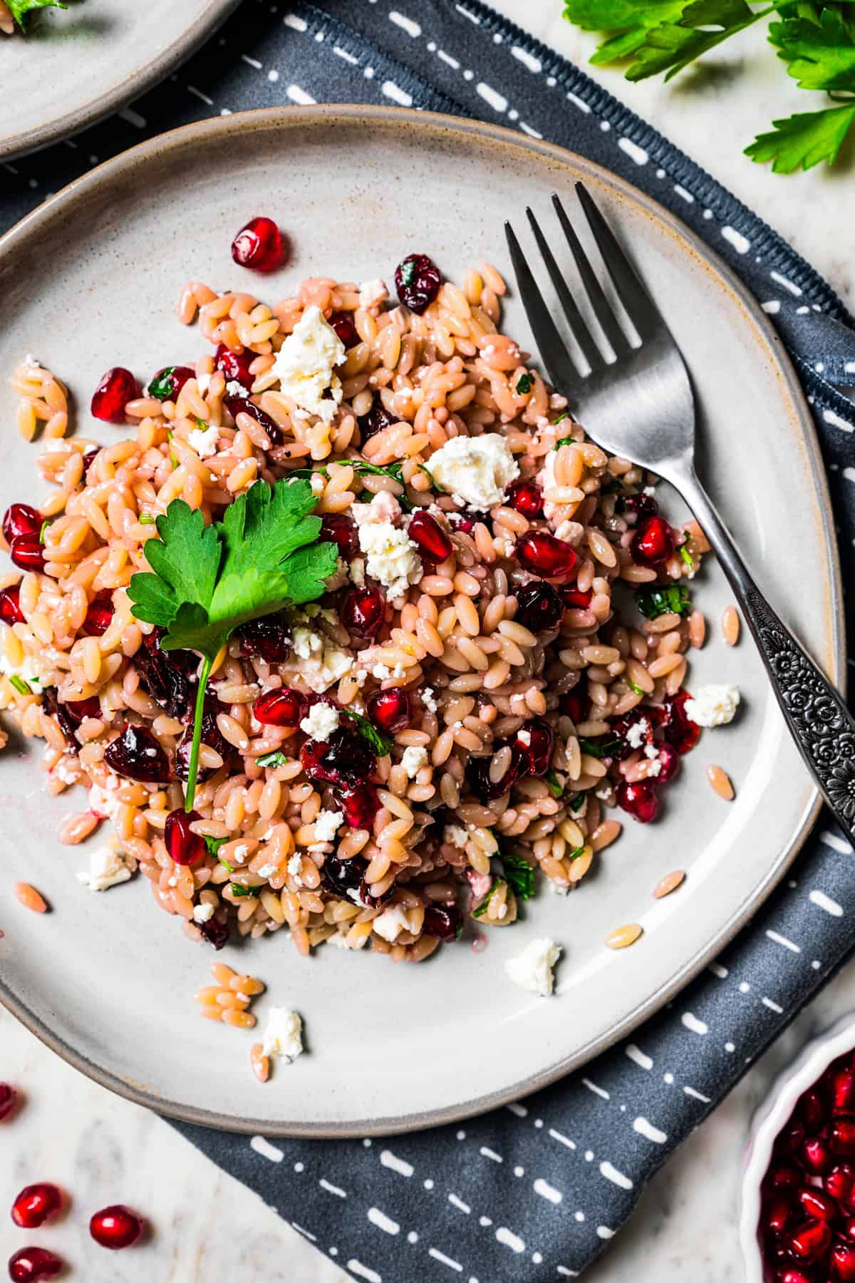 Orzo salad served on a salad plate with a fork set on the plate, next to the orzo.