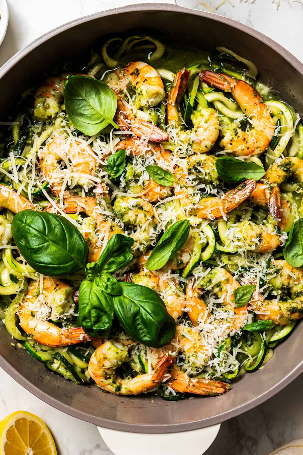 Zucchini noodles topped with shrimp and a garnish of fresh basil and cheese.