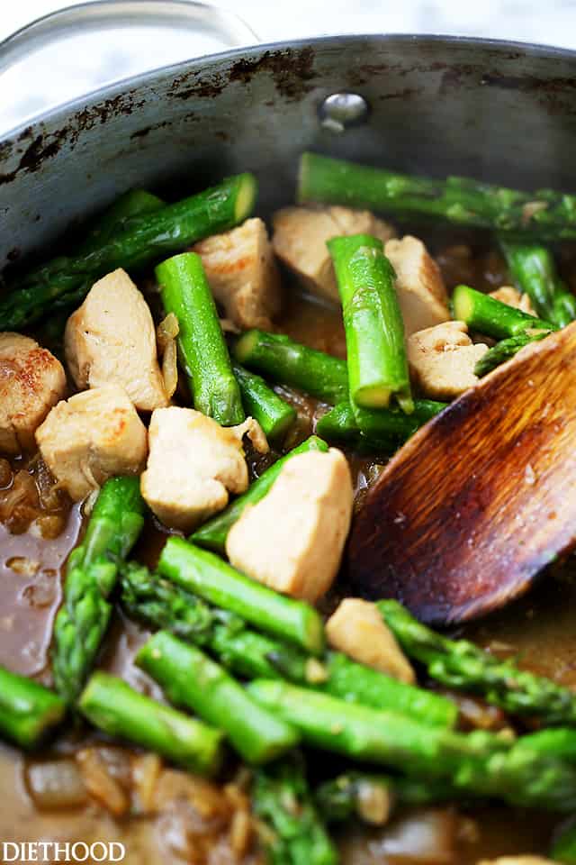 Asparagus cooking with chicken in chicken broth.