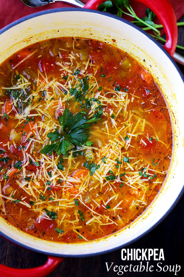 Overhead view of a pot of vegetable soup garnished with parsley and grated parmesan cheese.