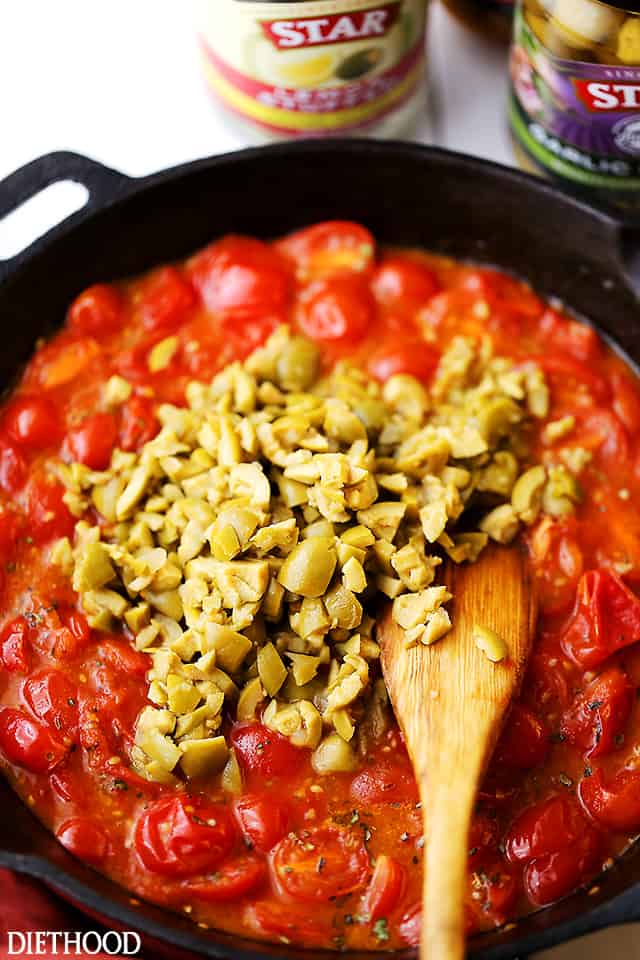 Cooking tomatoes and olives in a cast iron skillet.