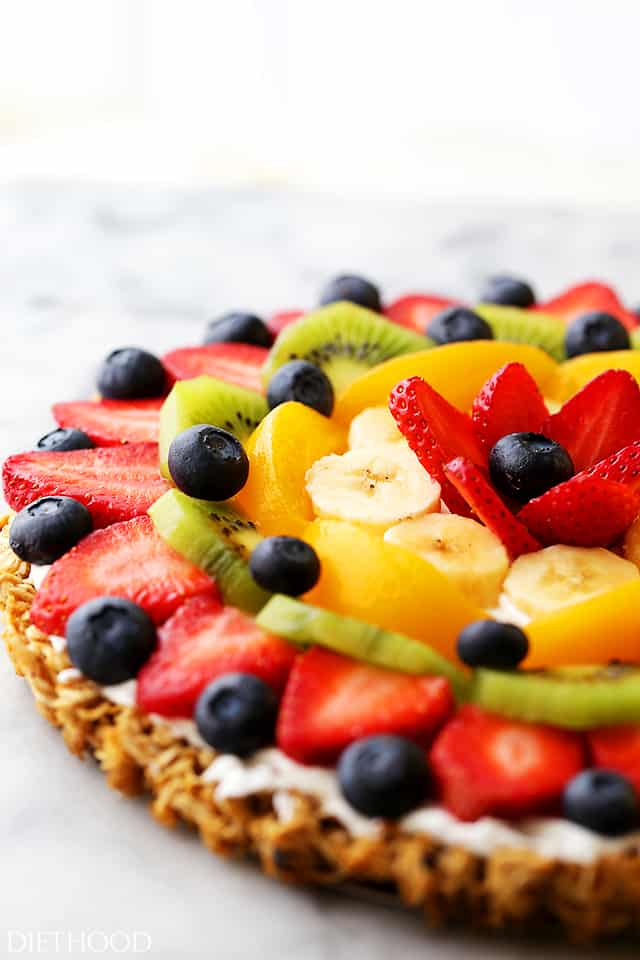 Close-up photo of a Fruit Pizza topped with berries, kiwi, bananas, and peaches.