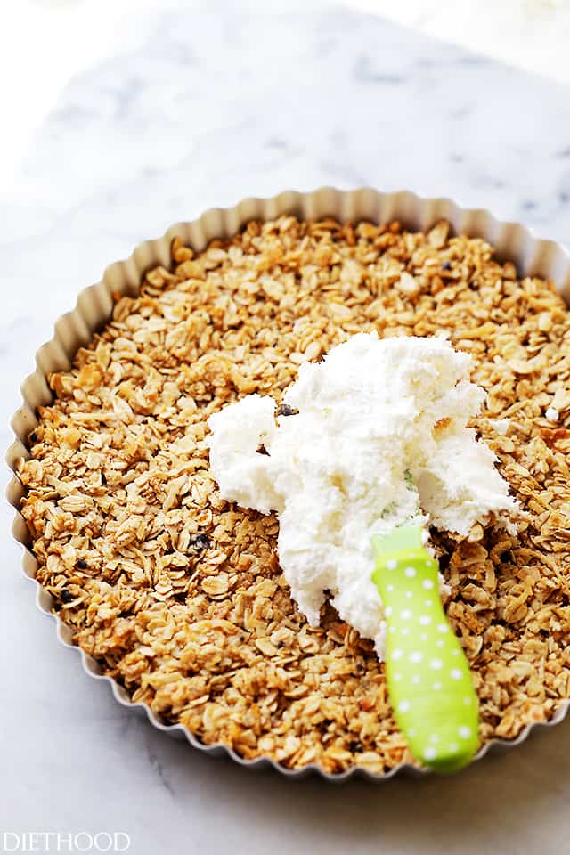 Spreading cream cheese frosting over a baked oatmeal crust.