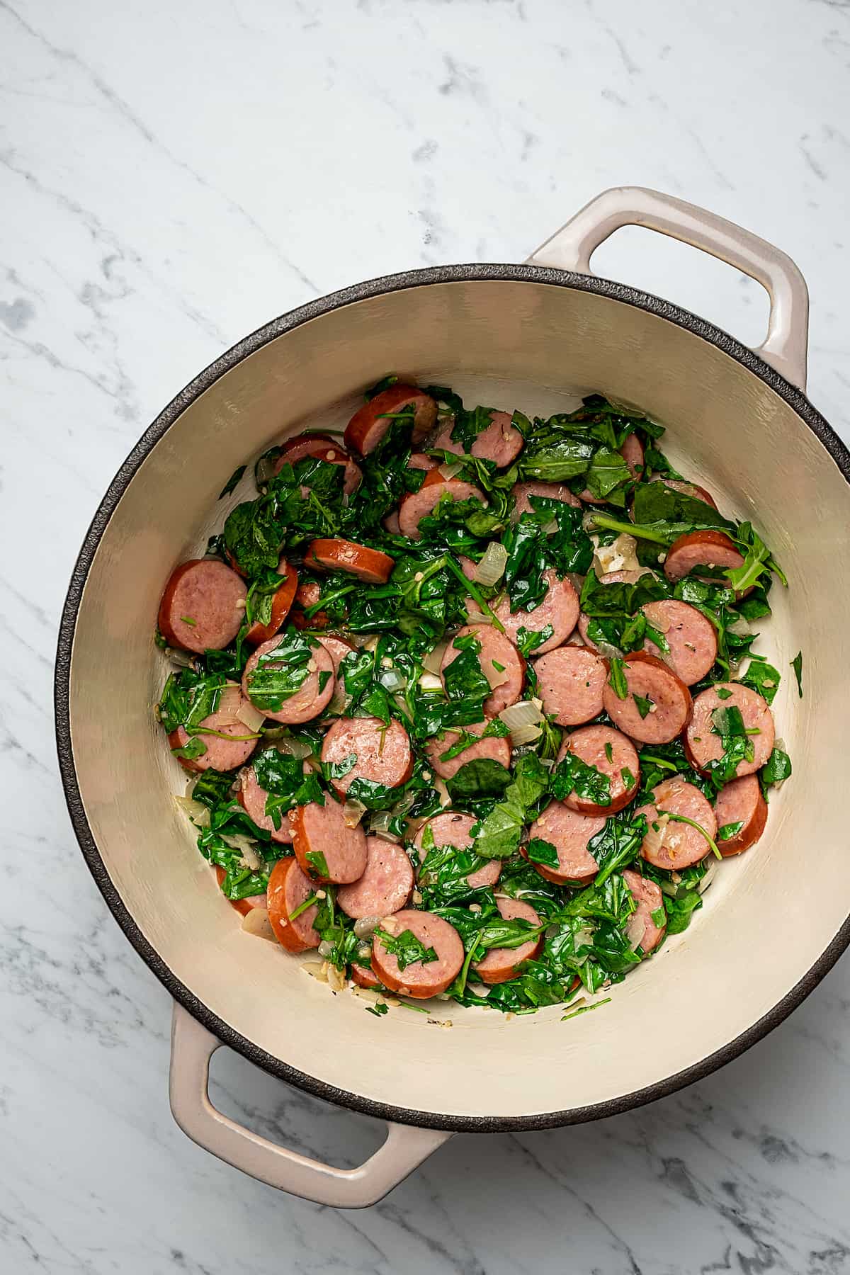 Sausage, kale, and other potato soup recipe ingredients cooking in a soup pot.